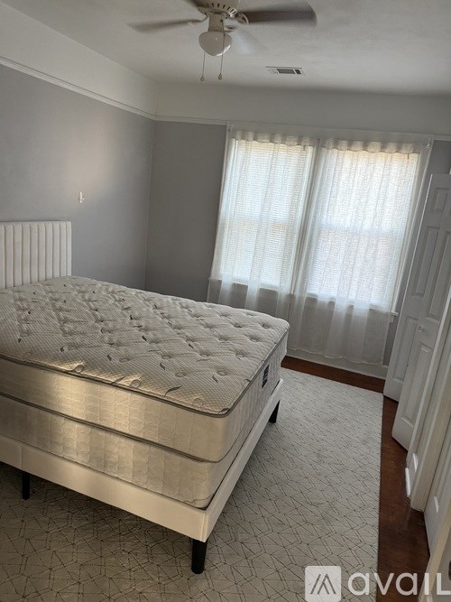 A bed with a white mattress and a fan on the ceiling.