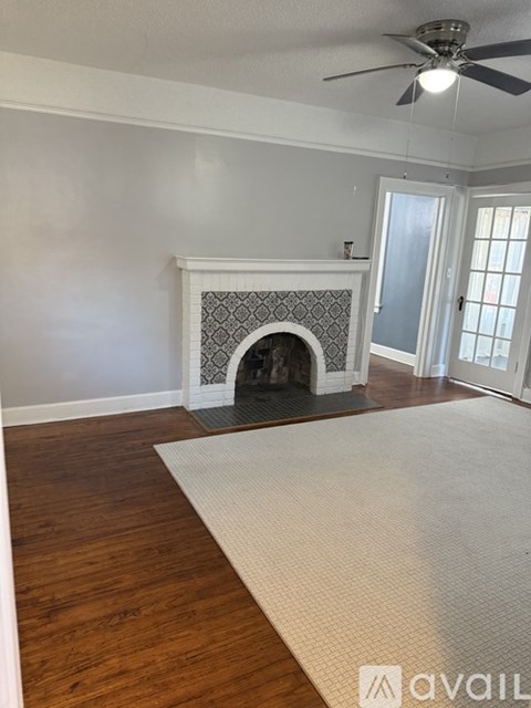 A living room with a fireplace and a rug on the floor.