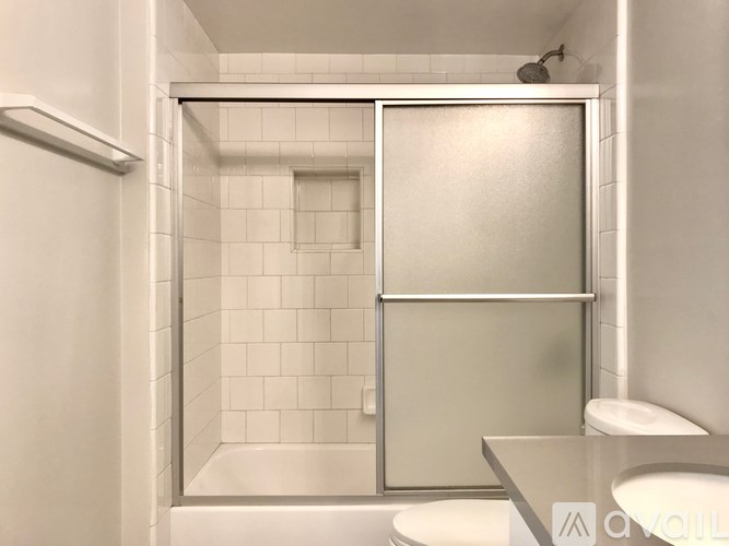 A white bathroom with a glass shower door and a toilet.