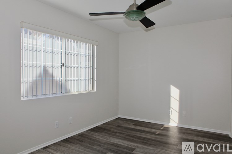 A room with a ceiling fan and a window with blinds.