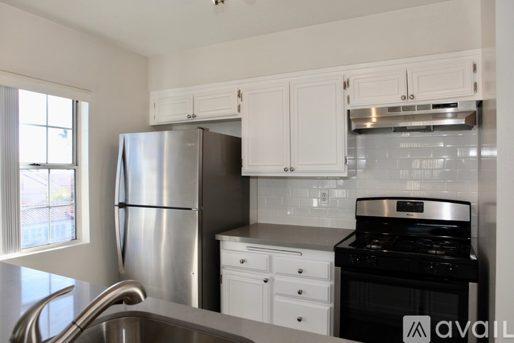 A kitchen with white cabinets and a stainless steel refrigerator.