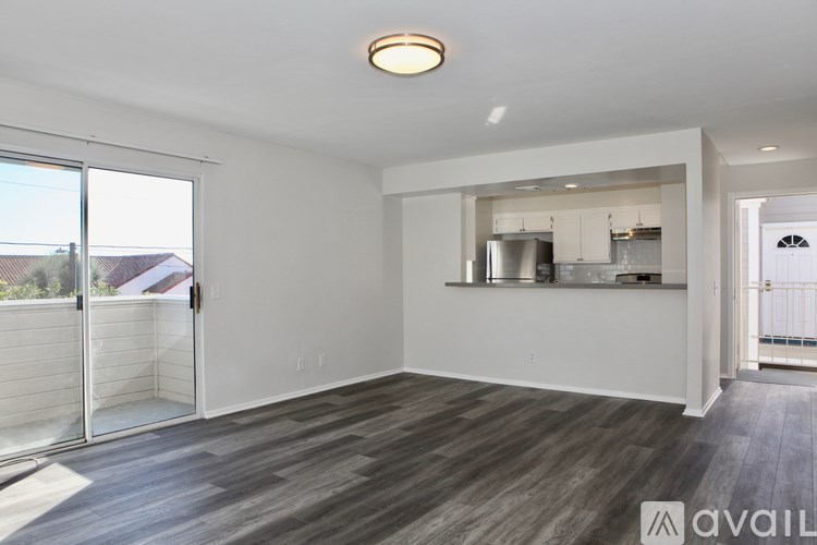 A spacious living room with a kitchen in the background and a sliding glass door.