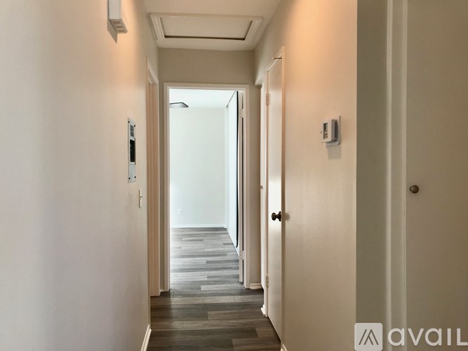 A hallway with a wooden floor and white walls.
