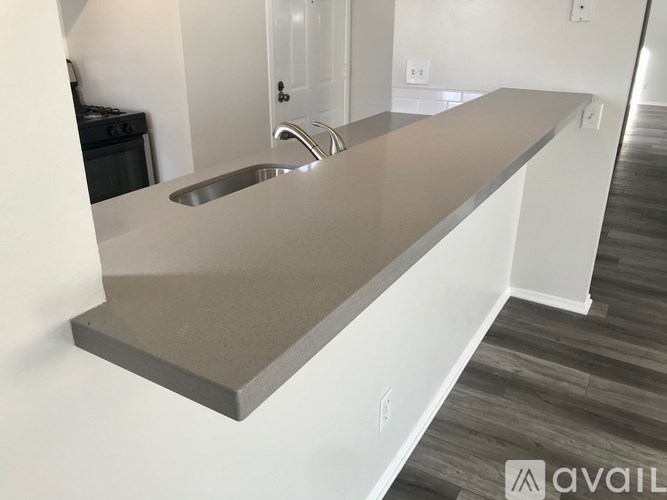 A kitchen counter with a sink and a stove in the background.