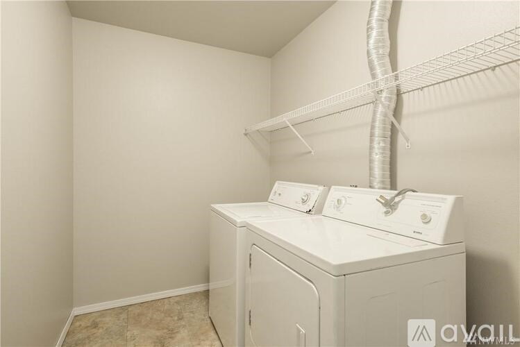 A white dryer and washer are sitting on top of a white cabinet in a small room.
