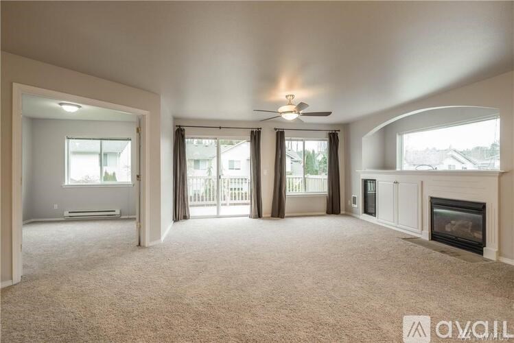 A spacious living room with a fireplace and a ceiling fan.