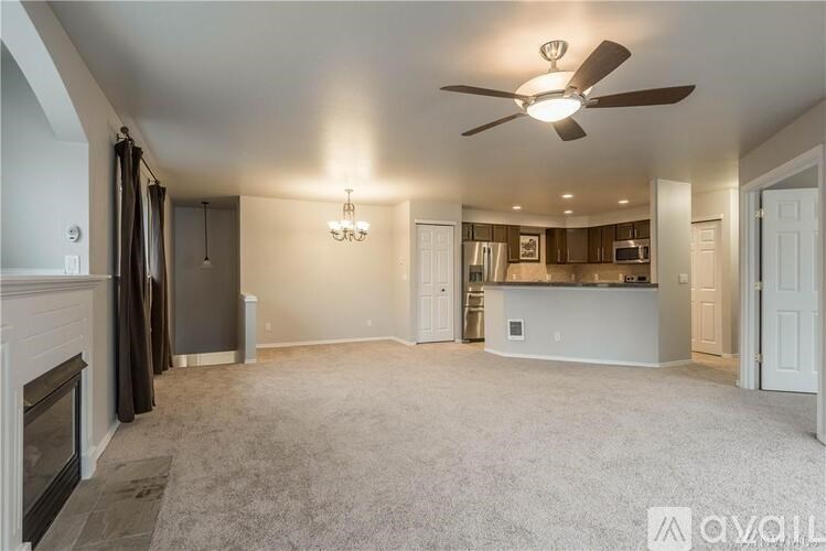 A spacious living room with a fireplace and a ceiling fan.