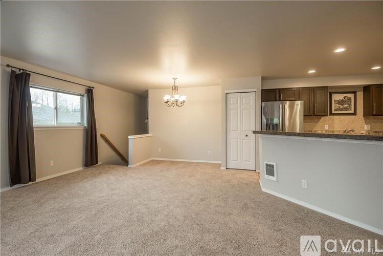 A spacious living room with a kitchen area in the background.