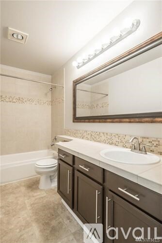 A bathroom with a toilet, sink, and mirror.