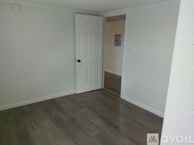 A room with a white door and wooden flooring.
