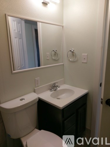 A bathroom with a toilet, sink, and mirror.