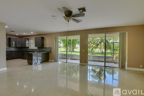 A spacious kitchen with a ceiling fan and a view of the outdoors through the sliding glass doors.