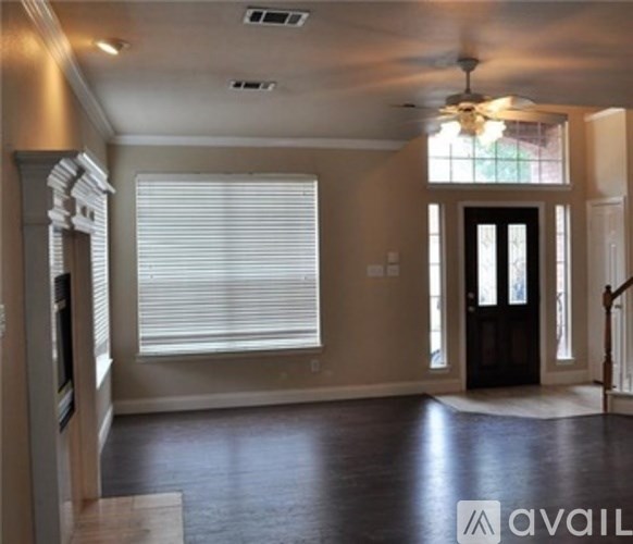 A spacious living room with a dark wood floor and a ceiling fan.