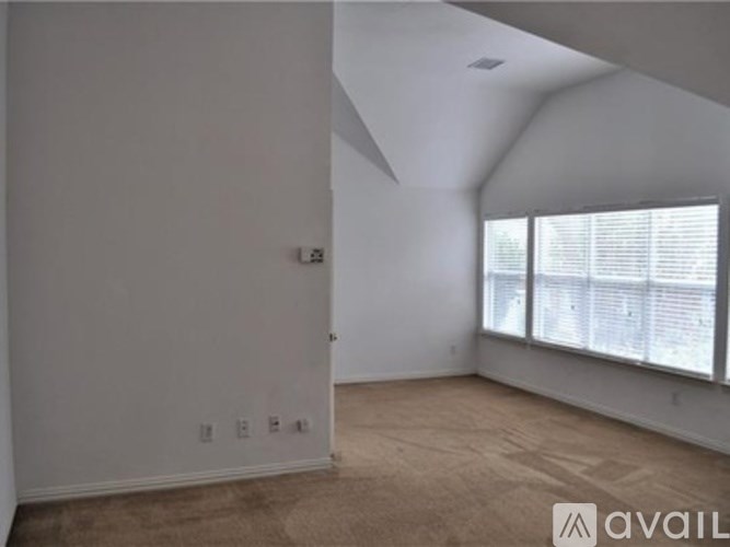 A room with a window and a carpeted floor.