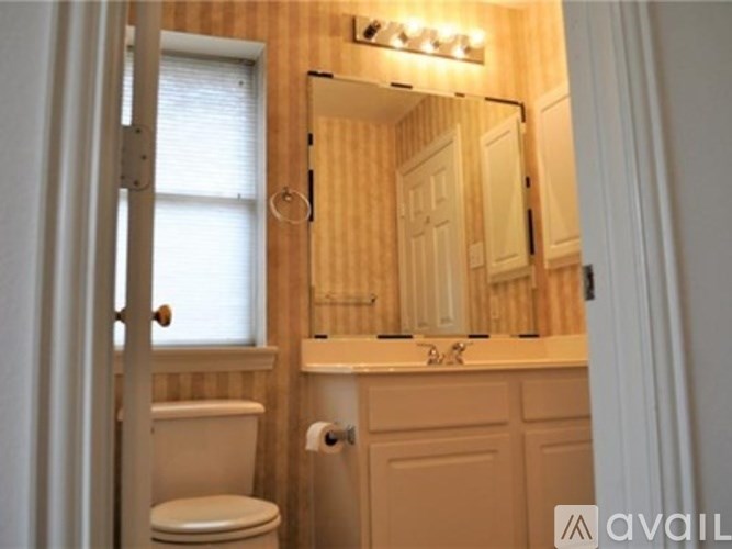 A bathroom with a toilet, sink, and mirror.