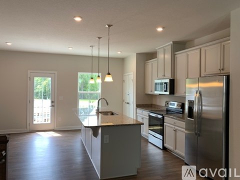 A modern kitchen with stainless steel appliances and pendant lights.