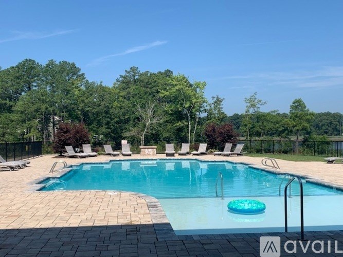 A pool surrounded by trees and chairs.