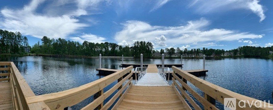 A wooden dock extends into a calm lake with a dock on the other side.