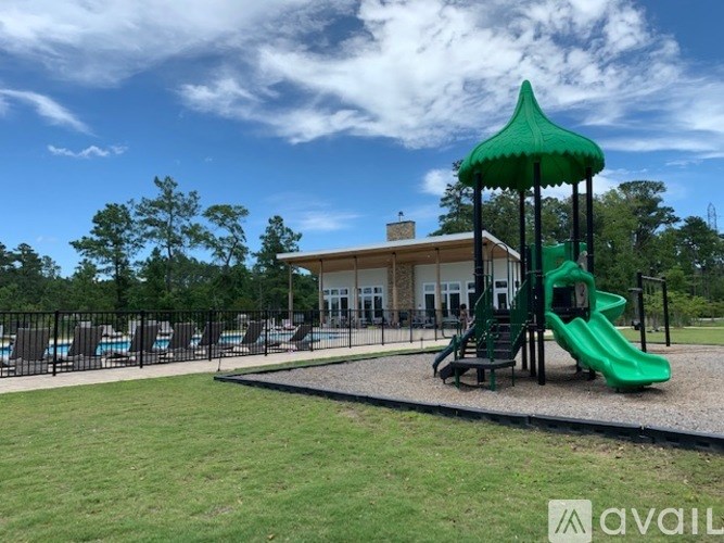 A playground with a green slide and a building in the background.
