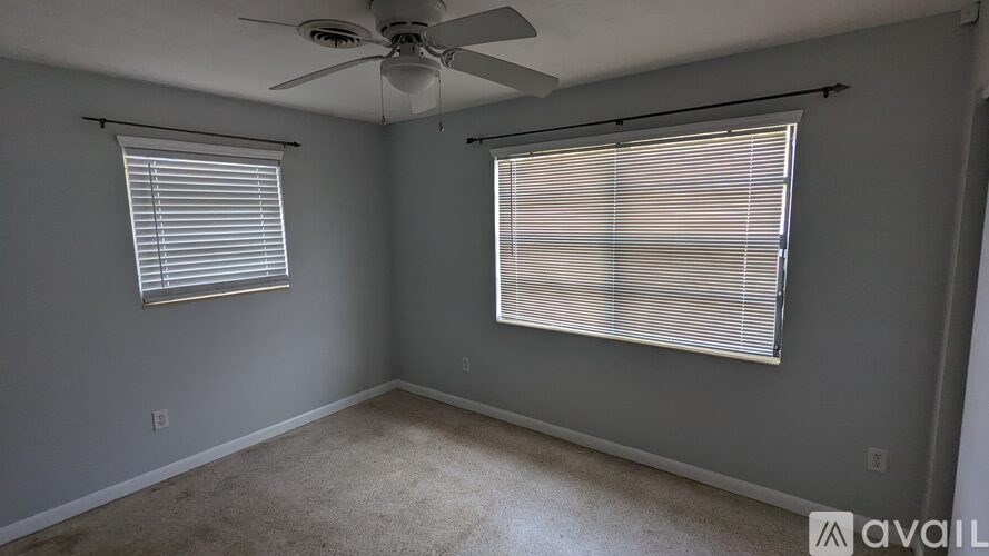 A room with a ceiling fan and two windows with blinds.