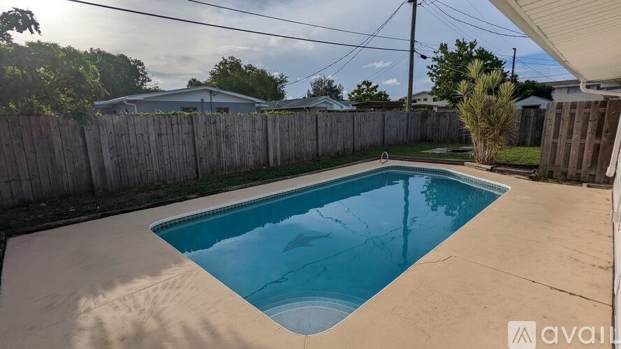 A small residential pool surrounded by a wooden fence.