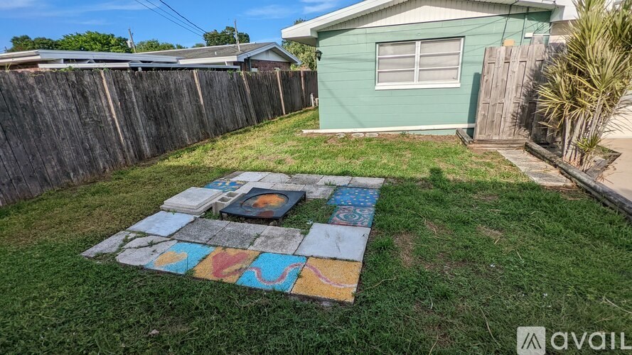 A backyard with a green fence and a blue house.