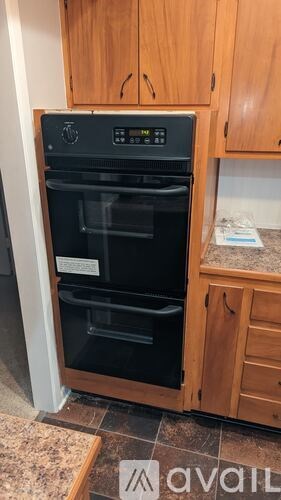 A black oven with a digital display is installed in a kitchen.