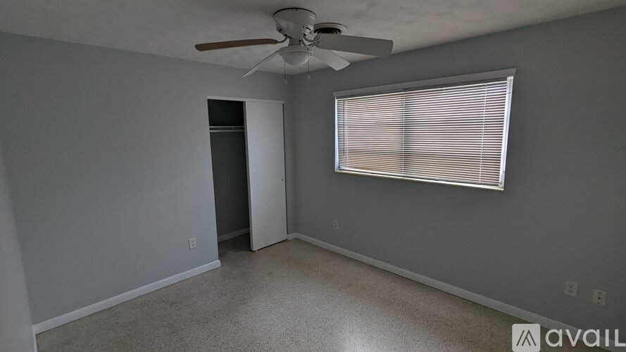 A room with a ceiling fan and a window with blinds.