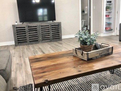 A living room with a wooden coffee table and a TV on a stand.