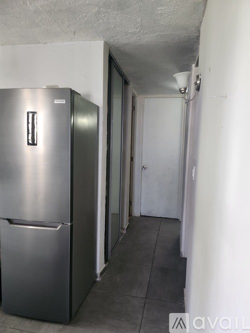 A silver fridge in a room with a white door.