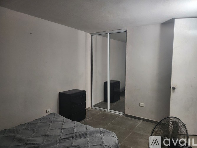 A bedroom with a bed, a black box, and a fan.