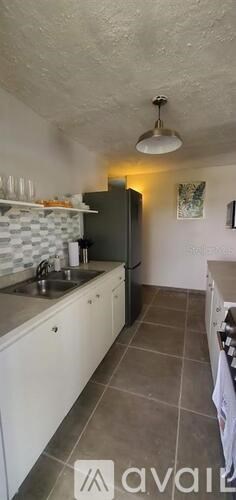A kitchen with a refrigerator, sink, and cabinets.