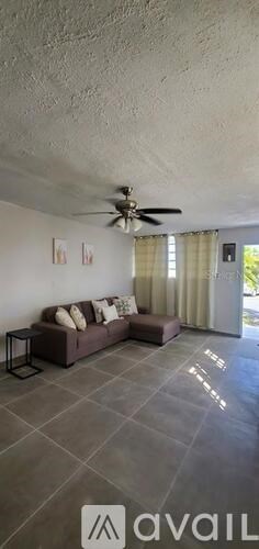 A living room with a brown couch and a ceiling fan.