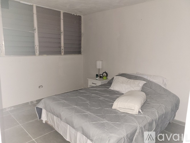 A bedroom with a bed, nightstand, and lamp.