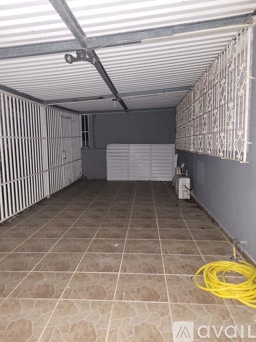 A room with a tiled floor and a yellow hose on the ground.