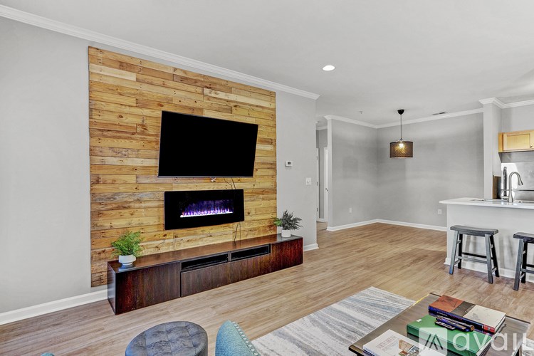 A living room with a wooden wall and a flat screen TV mounted above a fireplace.