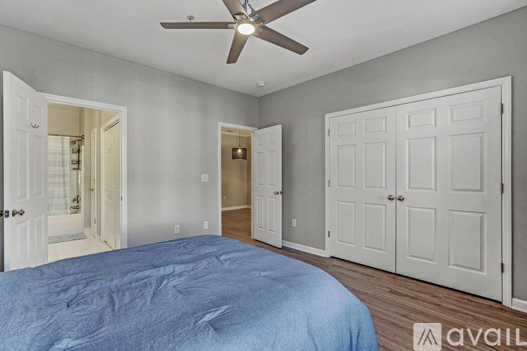 A bedroom with a blue bedspread and a ceiling fan.
