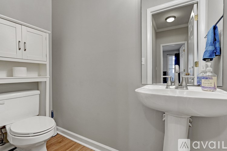 A bathroom with a white toilet, sink, and cabinets.
