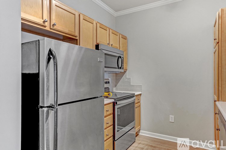 A kitchen with a stainless steel refrigerator and wooden cabinets.