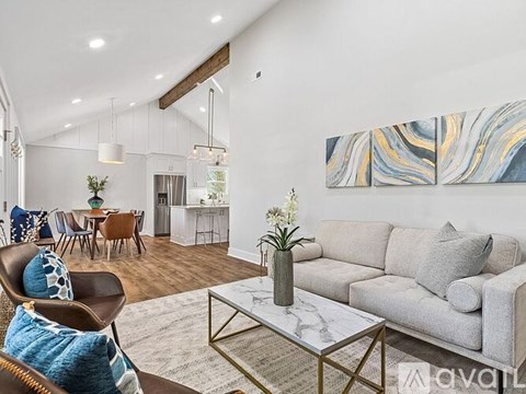 A living room with a grey couch, a coffee table, and a painting on the wall.