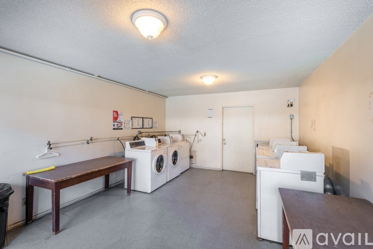 A laundry room with a washer and dryer, a table, and a trash can.
