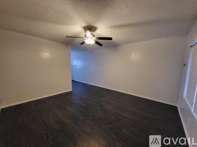 A room with a ceiling fan and wooden flooring.