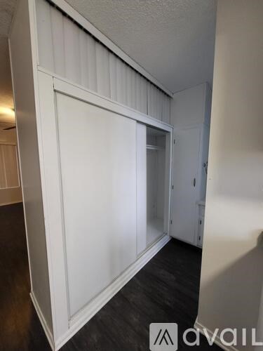 A white door is in a hallway with wood floors.