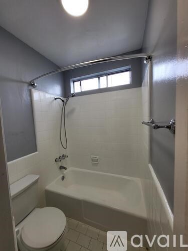 A bathroom with a toilet, tub, and window.