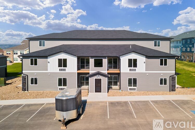 A large grey building with a parking lot in front of it.