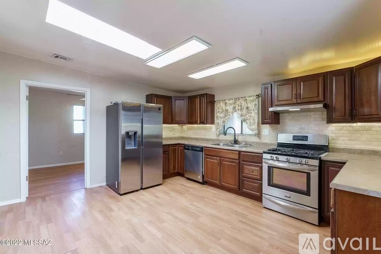 A kitchen with wooden cabinets and a stainless steel refrigerator.