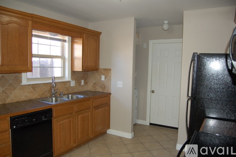 A kitchen with wooden cabinets and a black dishwasher.