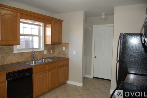 A kitchen with wooden cabinets and a black dishwasher.