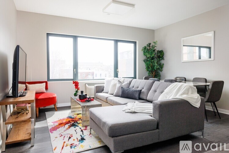 A living room with a grey couch, a red chair, a television, and a plant.
