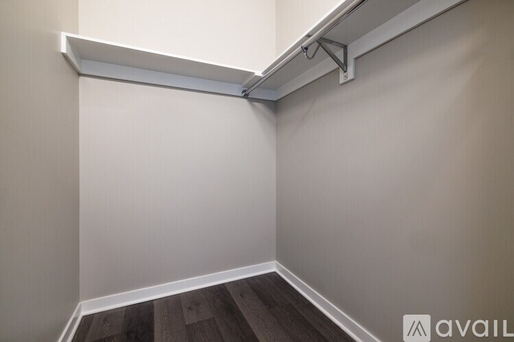 A corner of a room with a white wall and a wooden floor.
